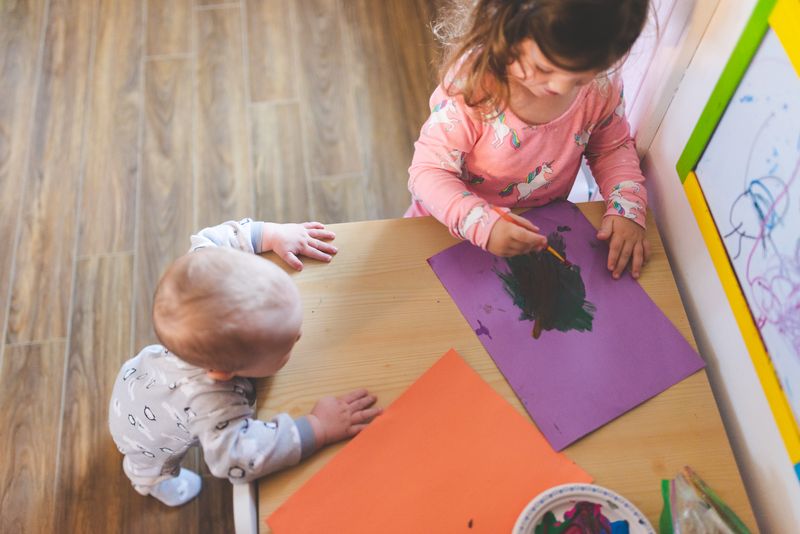 Dos niños pintando juntos sobre una mesa