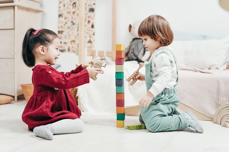 Dos niños armando una torre de bloques de madera